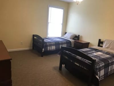 Private resident room with two beds and a dresser