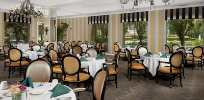 Dining room with elegantly set tables and views of the garden