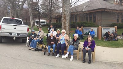 Residents enjoying time outdoors in front of the facility.