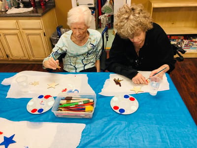 Two residents engaged in a craft activity at a table