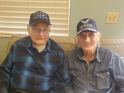 Two veterans smiling in a cozy indoor setting