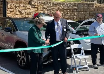 Two people cutting a ribbon at an outdoor event