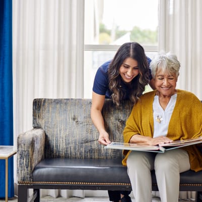 A caregiver and resident looking at a photo album together