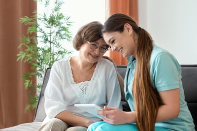 A caregiver and resident sharing a moment with a tablet
