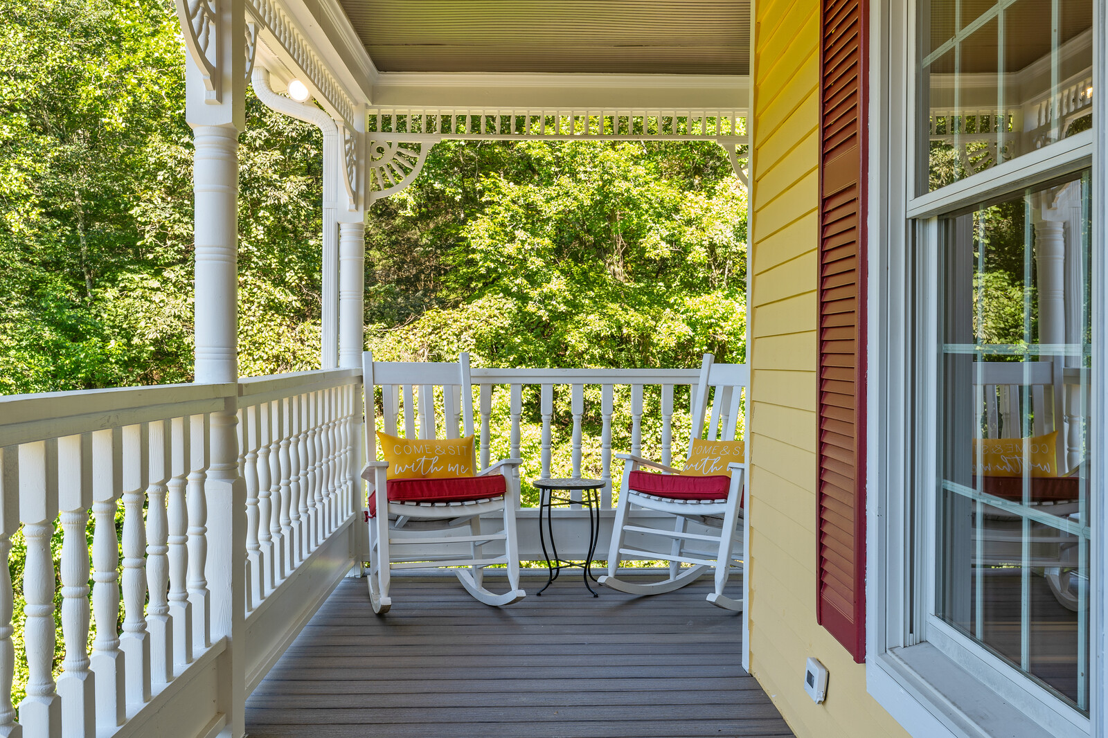 Rocking chairs on a porch surrounded by greenery