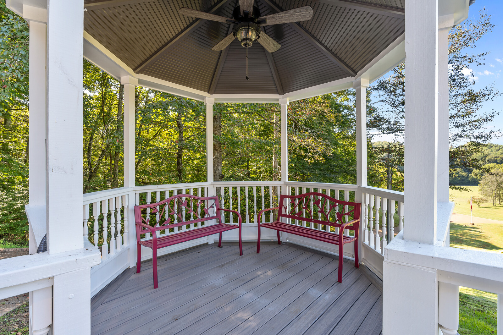 Outdoor gazebo area with seating and surrounding trees