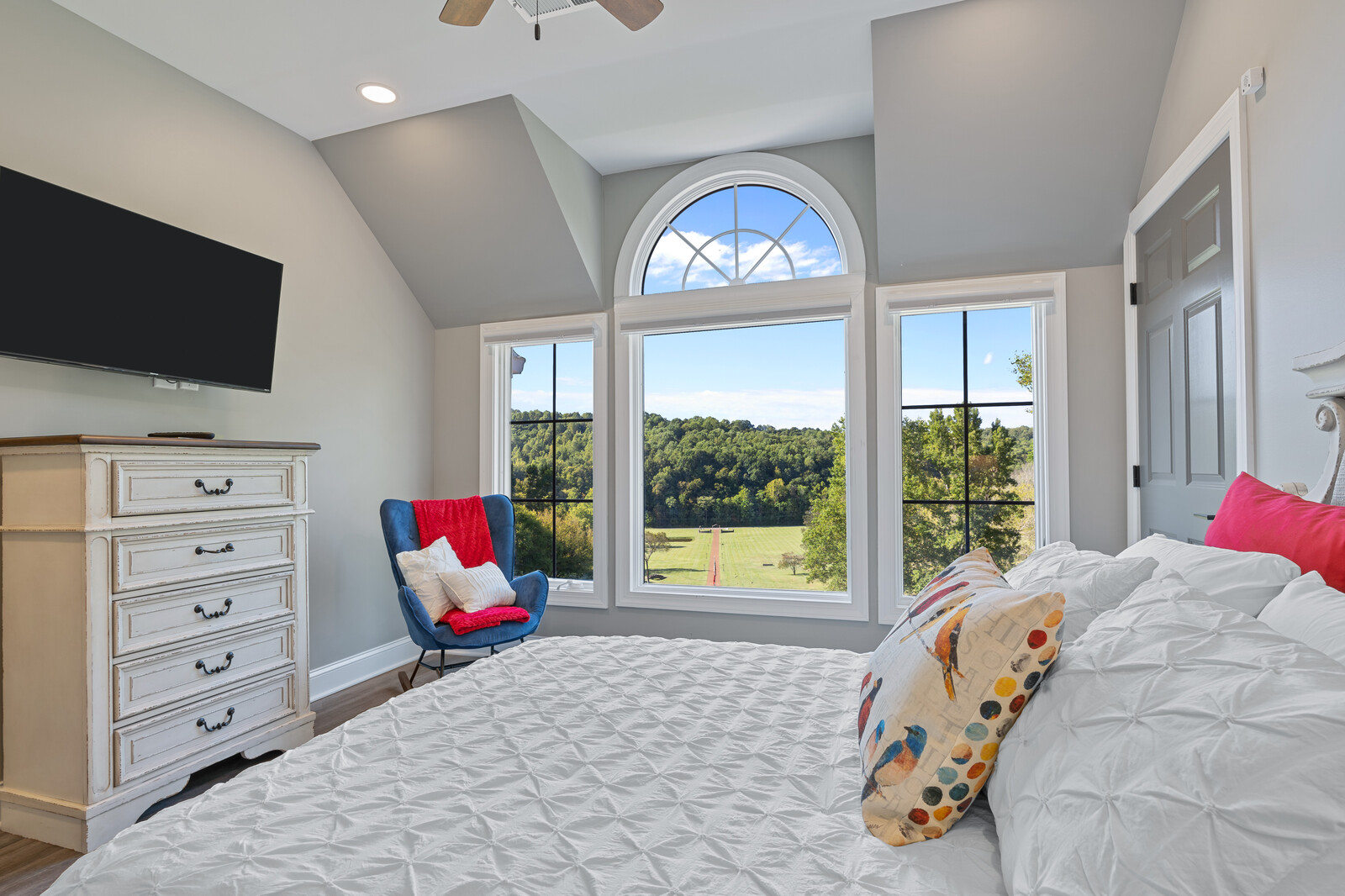 Spacious bedroom with large windows overlooking greenery