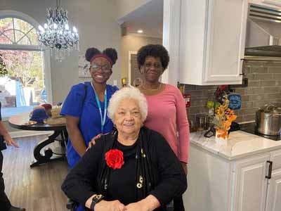 Residents and staff smiling together in the kitchen area