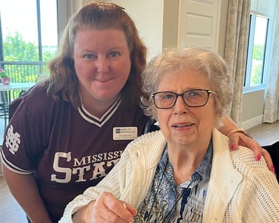 A resident and staff member smiling together in a common area