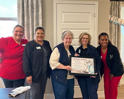 Staff and resident celebrating with a framed prayer