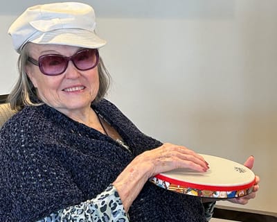 Resident playing a drum in a cozy setting