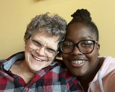 Two smiling individuals, a resident and a staff member, posing together.