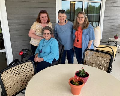 Residents and staff on a patio with potted plants