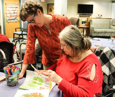 A resident and staff member engaged in an art activity