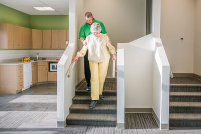 Staff assisting a resident down the stairs in a common area