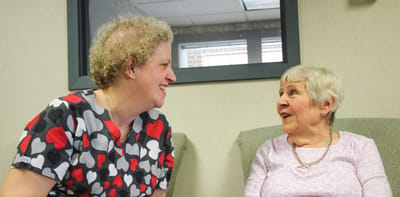Staff member conversing with a resident in a cozy lounge