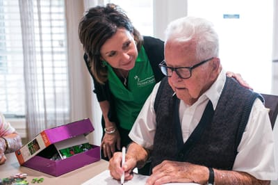 Staff assisting a resident with an activity in a common area