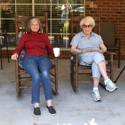 Residents enjoying rocking chairs on a porch