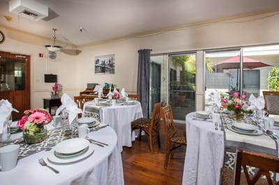 Dining area set up for a meal with flowers and table settings