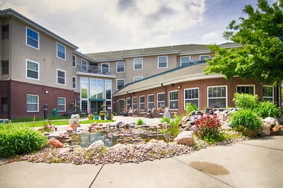 Exterior view of The Lexington Assisted Living with garden and pond