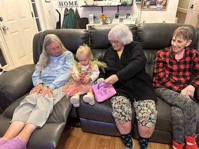 Residents interacting with a young child in a cozy living room