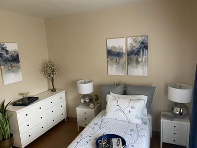 A well-decorated private resident room with a bed and artwork
