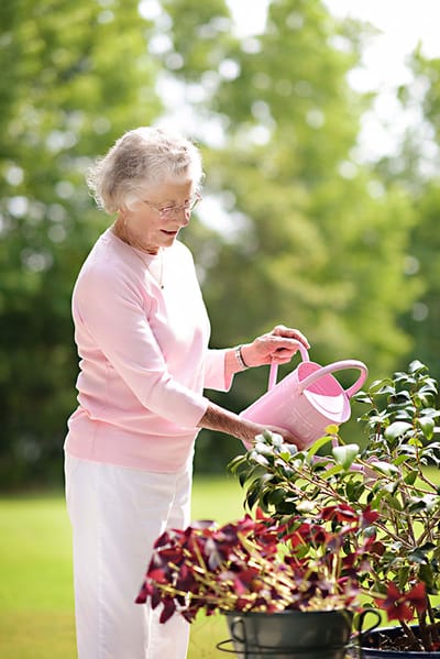 Benton House of Grayson, assisted living in Grayson, GA — Senior woman watering potted plants in a garden