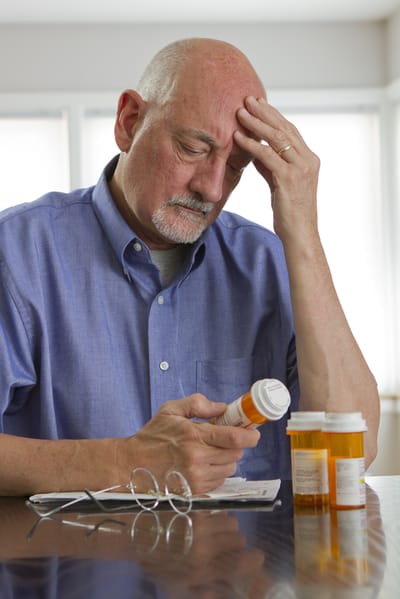 Benton House of Grayson, assisted living in Grayson, GA — Man examining prescription medication bottles at a table