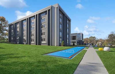 Exterior view of a senior living facility with a lawn and walkway