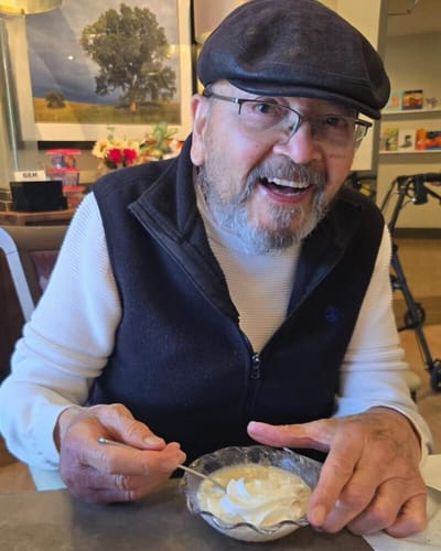 A smiling resident enjoying dessert in a common area