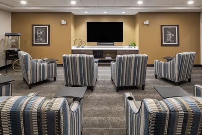 A comfortable lounge area with striped chairs and a TV