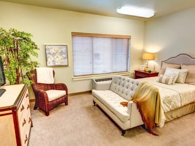 A well-furnished private resident room with a bed and seating area