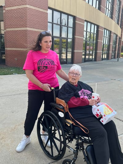 Caregiver assisting a resident outdoors near the building