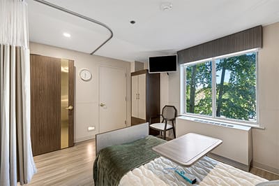 Bright interior of a private resident room with a bed and window