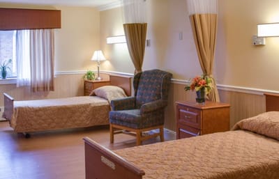 Cozy resident room with two beds and a chair