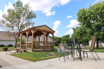 Outdoor gazebo area with seating and greenery