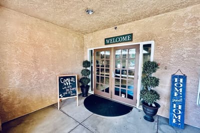 Entrance with a welcoming sign and decorative plants