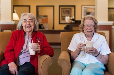 Two residents enjoying milkshakes in a lounge area