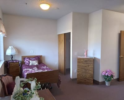 A cozy resident room with a decorated bed and furniture
