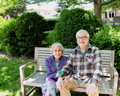 Elderly couple sitting on a bench in a garden