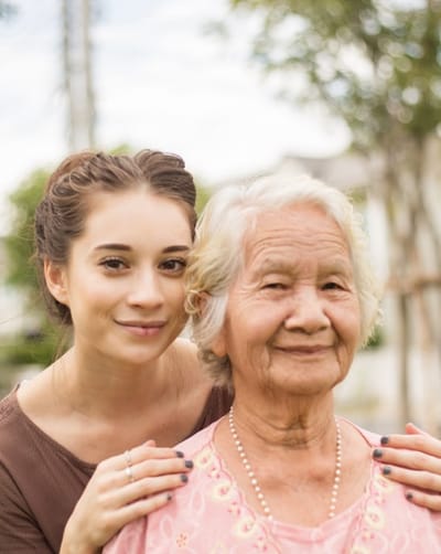 A caregiver and resident smiling outdoors