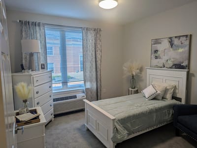 Bright private resident room with a twin bed and furnishings