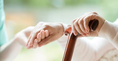 Hands of a caregiver holding the hand of a senior person