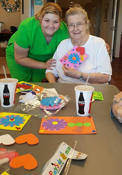 Staff member and resident crafting together in an activity room
