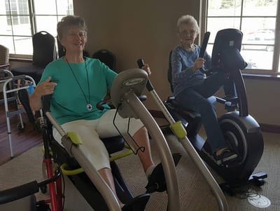 Two elderly women exercising on recumbent bikes