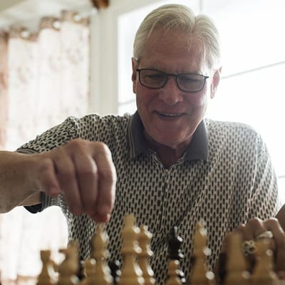 Senior man playing chess in a bright room
