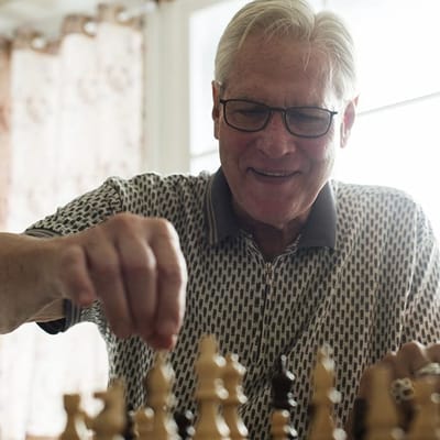 A resident enjoying a game of chess indoors