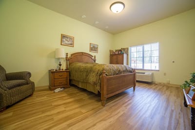 A cozy resident room with a bed and chair