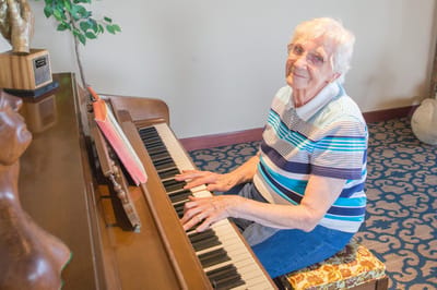 Resident playing piano in a facility common area
