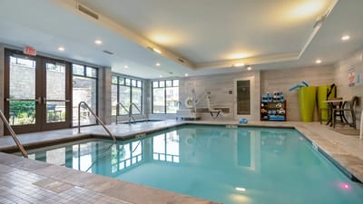 Indoor pool area with lounge chairs and windows